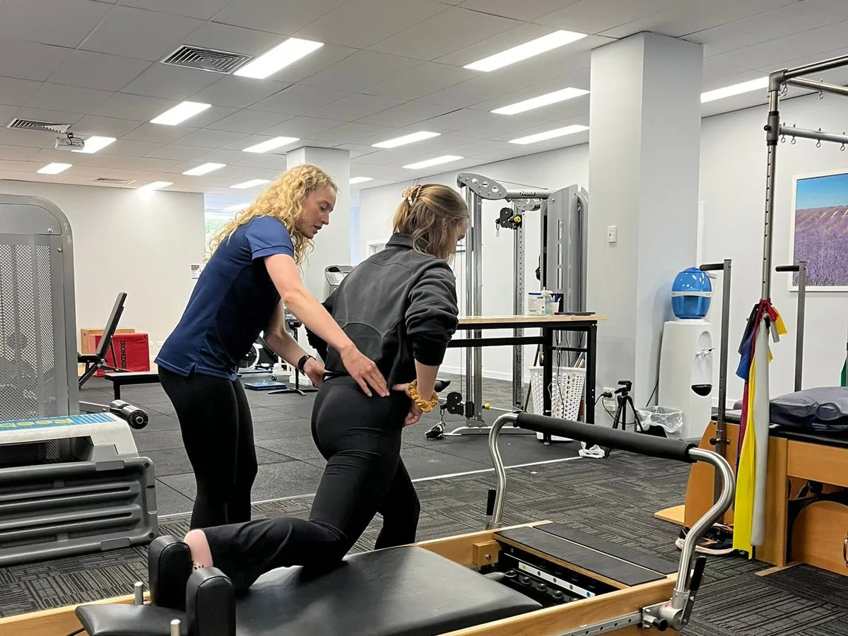 Clinical Pilates physiotherapist coaching a patient on a reformer in the Complete Physio Richmond gym