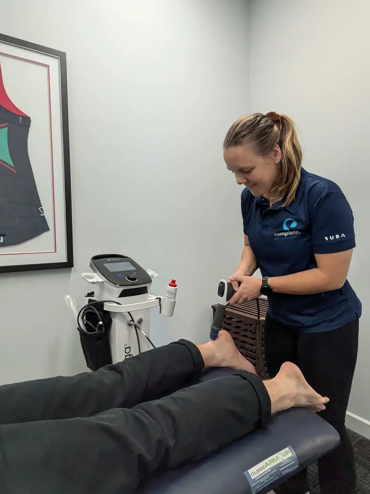 Physiotherapist treating a patient's foot with shockwave therapy at Complete Physio in Richmond