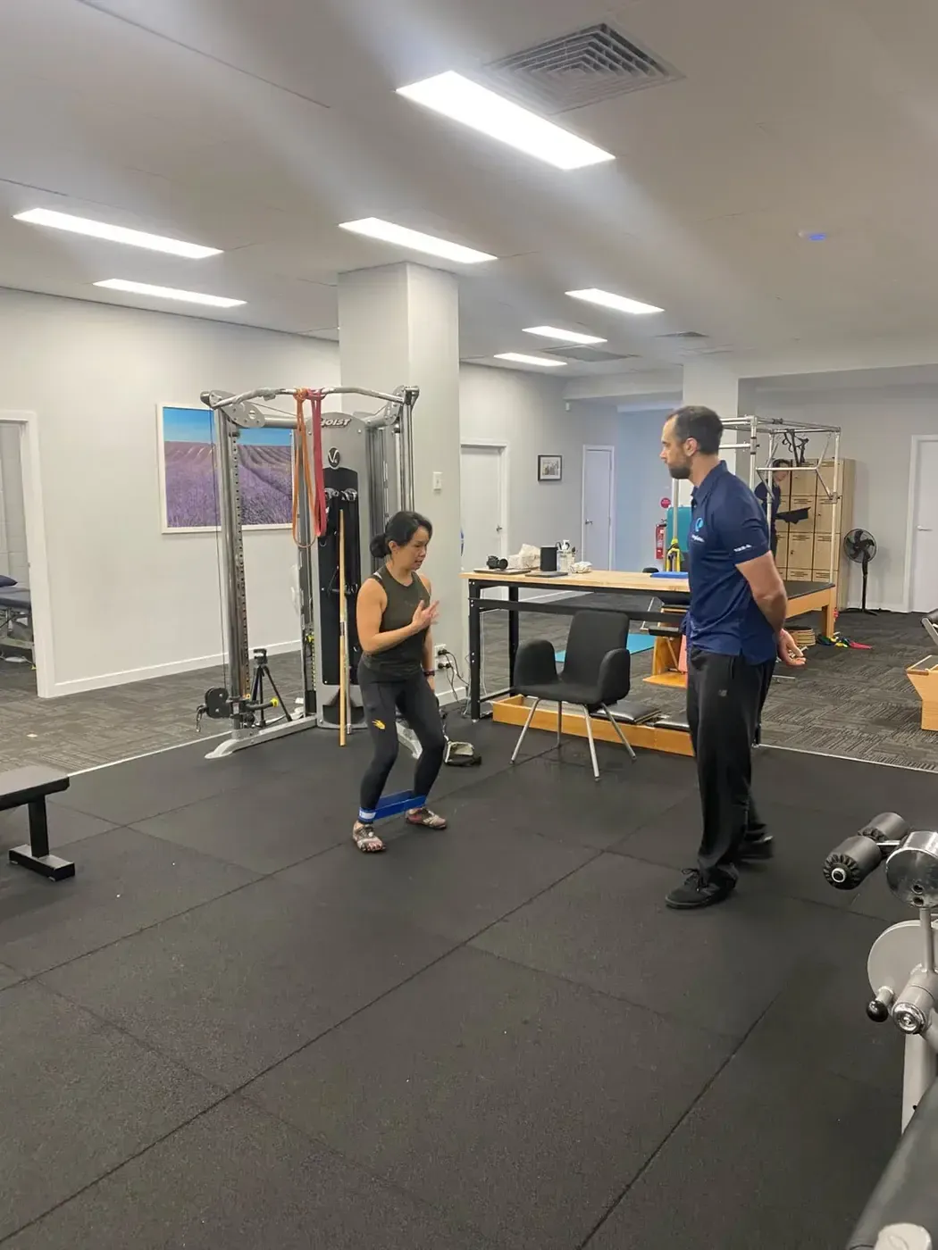 Client performing a banded squat under supervision from strength and conditioning coach James Ross at Complete Physio Richmond